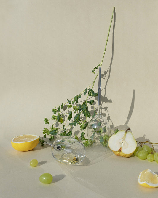 2 pointer wine glasses photographed next to halved pear, lemon halves and plants