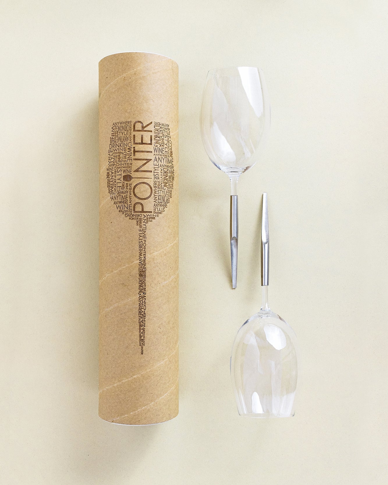 2 picnic wine glasses for red wine laying next to each other and next to cardboard packing tube