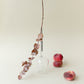 one wine glass for picnic with metal pin, placed upside down next to peaches and a plant branch