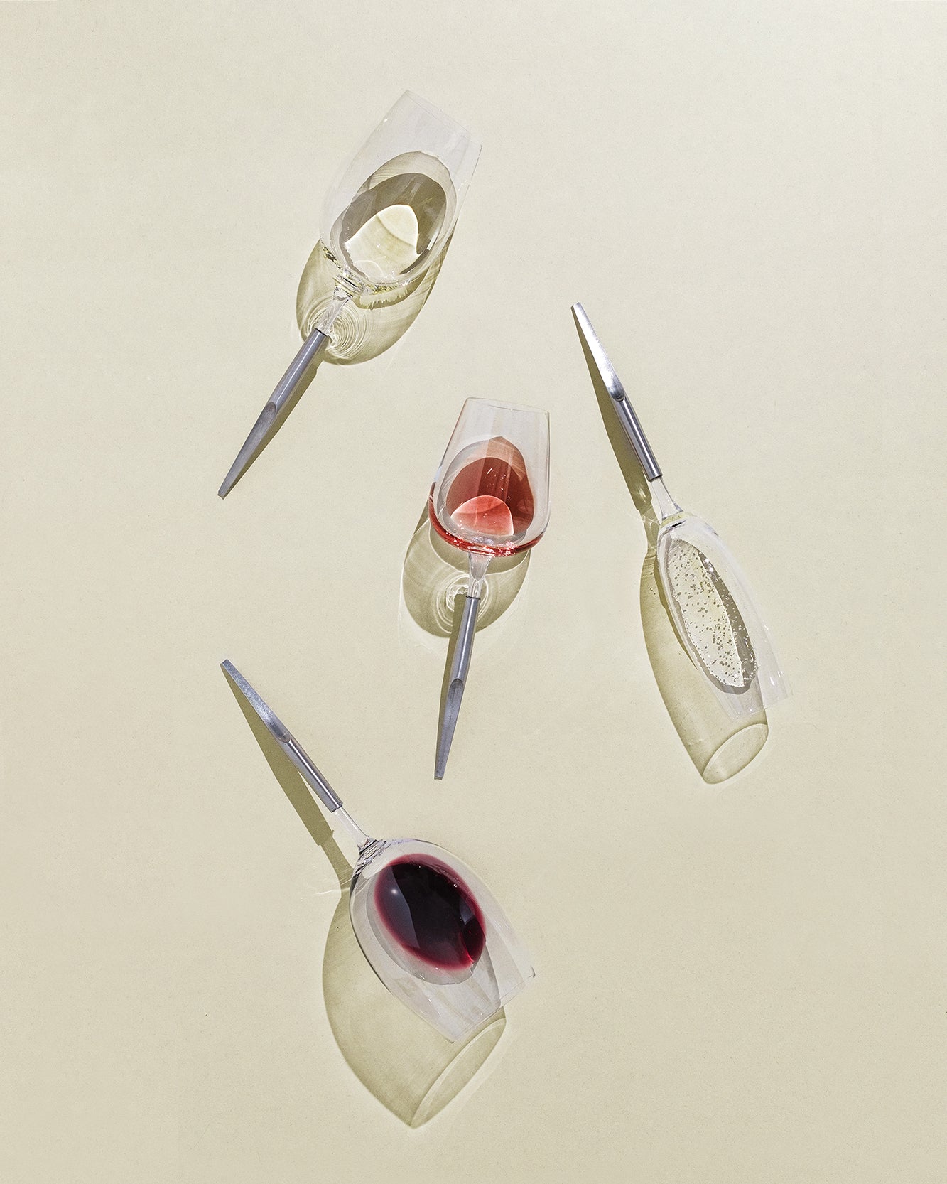 picnic wine glasses with metal pin for white wine, red wine and champagne, placed horizontally on a beige background and half filled with wine