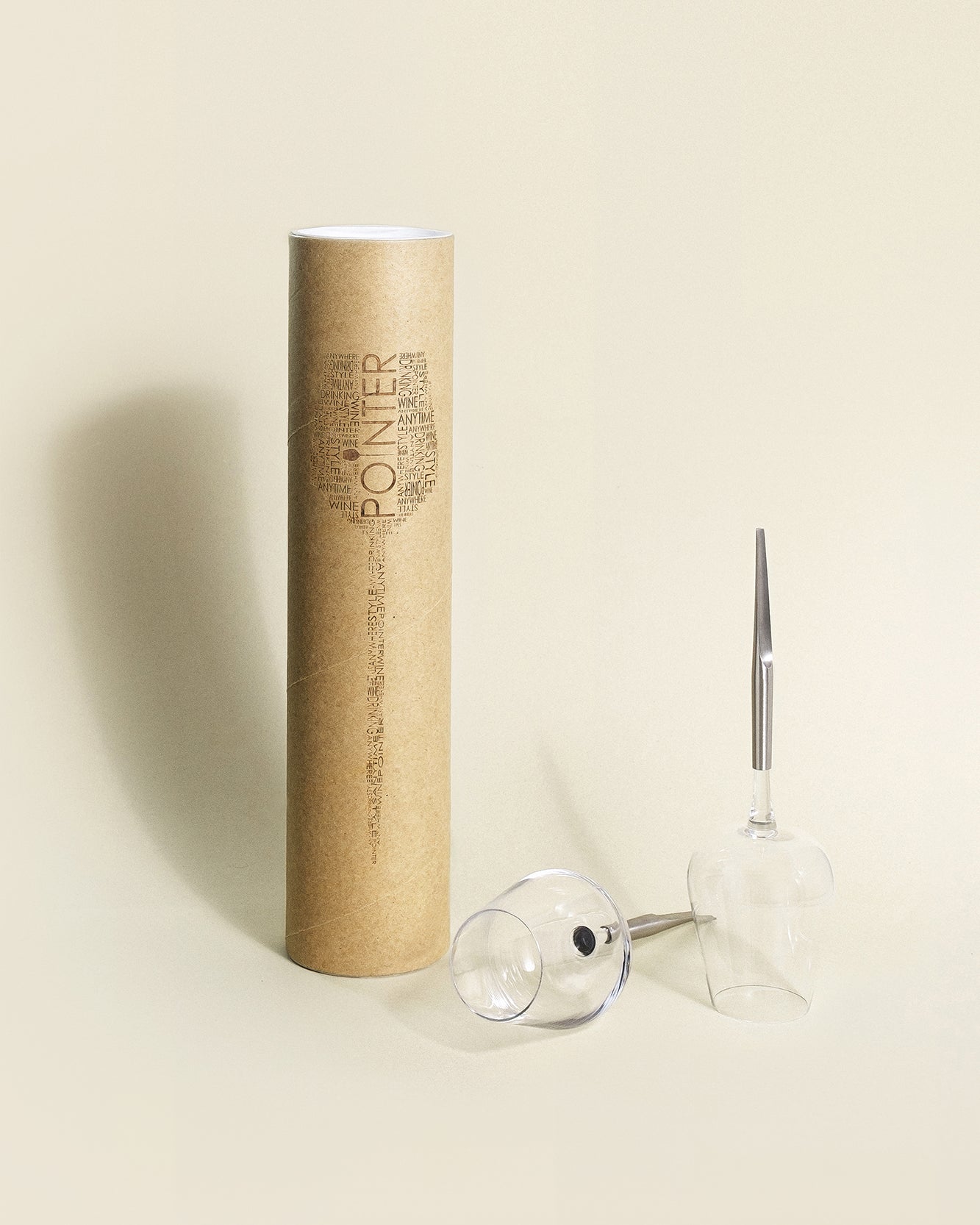 2 picnic wine glasses with metal pin, placed next to their cardboard packing tube for transport, one upside down, one horizontally